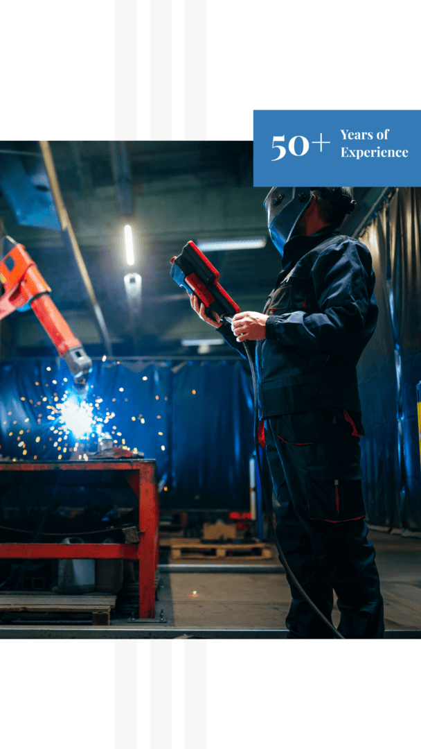 Welder operating robotic arm in workshop.